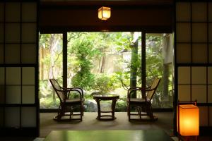 2 sillas y una mesa en una habitación con ventana en Izumiya Zenbe, en Matsumoto