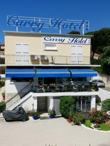 un bâtiment avec un restaurant doté d'un auvent bleu dans l'établissement Carry Hotel, à Carry-le-Rouet