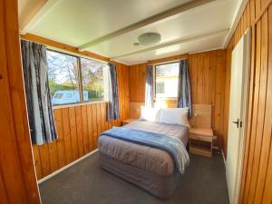 Habitación pequeña con cama y ventana en Whanganui River Top 10 Holiday Park, en Whanganui