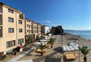uma praia com espreguiçadeiras e edifícios e o oceano em Palma Beach Hotel em Kranevo