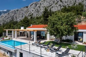 a house with a swimming pool in front of a mountain at Villa Kostela Makarska in Makarska