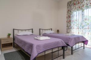 two beds in a bedroom with purple sheets and a window at ANEMOELIA II in Sykia Chalkidikis