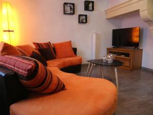 sala de estar con sofá naranja y TV en Gîte Fléville-Lixières, 4 pièces, 6 personnes - FR-1-584-166, 