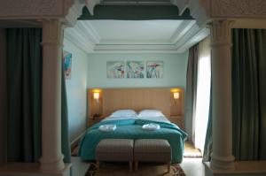 a bedroom with a green bed with two chairs at Hotel Palais Al Bahja in Marrakech