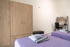 a room with two beds with purple sheets and wooden cabinets at ANEMOELIA II in Sykia Chalkidikis