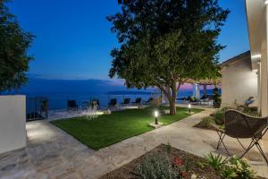 a patio with a lawn with chairs and a tree at Villa Kostela Makarska in Makarska