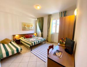 una camera d'albergo con due letti e una televisione di Albergo Villa Ada a Borgio Verezzi