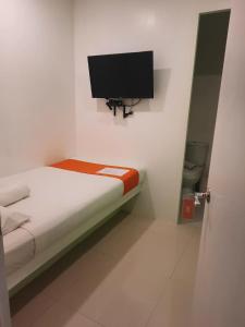 a small bedroom with a bed and a flat screen tv at Islands Stay Hotels Mactan in Mactan