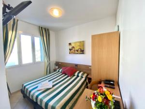 Schlafzimmer mit einem Bett, einem Tisch und einem Fenster in der Unterkunft Albergo Villa Ada in Borgio Verezzi