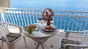 a little girl sitting at a table with a plate of food at Apartment Mustapic - Perfect view, first row, possibility of fishing in Klek
