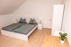 a white bedroom with a bed with green pillows at Gemütliche Ferienwohnung im Zentrum von Plauen in Plauen