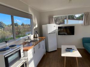 a kitchen with a sink and a refrigerator and a table at Whanganui River Top 10 Holiday Park in Whanganui