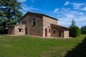 ein Steinhaus auf einem Grasfeld mit einem Baum in der Unterkunft Il Leccio in San Gimignano