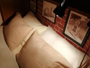 a bed with two pillows against a brick wall at Apartments Tamara in Sukošan