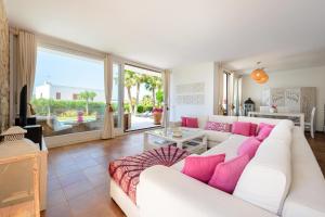 uma sala de estar com um sofá branco e almofadas cor-de-rosa em Can Rin em San Antonio Bay