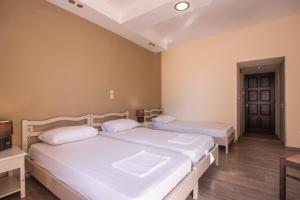 a bedroom with two beds and a tv and a door at Yria Hotel in Zakynthos Town