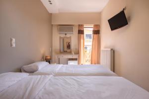two white beds in a room with a television at Yria Hotel in Zakynthos Town