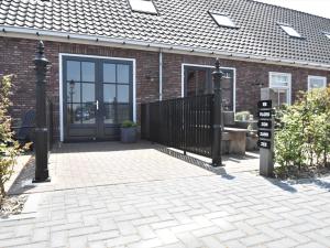 a brick house with a black gate and a door at Apartment near Groote Keeten Beach in Callantsoog