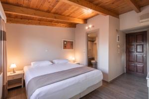a bedroom with a large white bed and wooden ceilings at Yria Hotel in Zakynthos Town