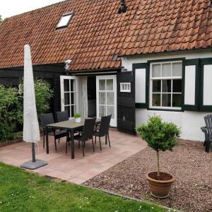 Un patio con mesa y sillas y una casa. en Ferienhaus Gapinge Walcheren Zeeland, en Veere