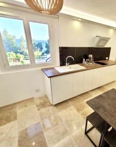 cocina con fregadero, mesa y 2 ventanas en Mer & Calme en Saint-Mandrier-sur-Mer