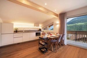 a kitchen and dining room with a table and a balcony at Engel Appartements Summerfrisch in Parcines