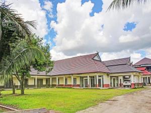 a large house with a red roof and a palm tree at OYO 90423 Hotel Aman in Palangkaraya