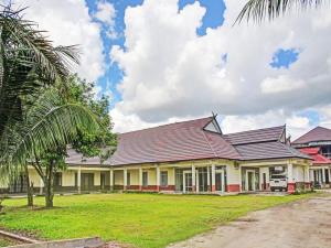 una casa grande con techo rojo y una palmera en OYO 90423 Hotel Aman en Palangkaraya