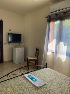 a bedroom with a bed and a tv and a chair at Affittacamere La Petra Longa in San Teodoro