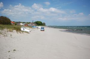 uma praia arenosa com barcos ao lado do oceano em Schlafstrandkorb Nr. 3 em Sierksdorf