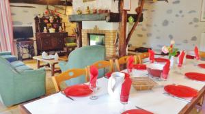 a dining room with a table with red plates and chairs at Le gîte d'en haut in Jarret