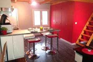 a kitchen with red walls and a counter with stools at Joli studio entre mer et montagne proche de Nice in Bouyon