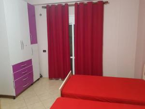 Schlafzimmer mit roten Vorhängen und einem roten Bett in der Unterkunft LUXURY SEASIDE APARTMENT WITH TWO BEDROOMS 130 meter in Vlorë