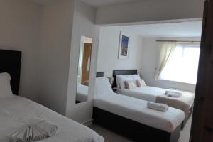 ein Hotelzimmer mit zwei Betten und einem Spiegel in der Unterkunft Capri Guest House in Torquay + 14 Fotos