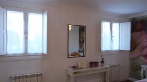 baño con paredes y ventanas blancas y espejo en HOTEL LA CASA DE LAS CAMELIAS, en Busto