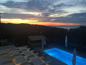 uma piscina com cadeiras e um pôr-do-sol ao fundo em Villa Elaia Suites & Apartments No.6 em Gaios