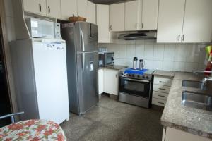 cocina con armarios blancos y nevera en Pousada 45 Hostel, en Belo Horizonte