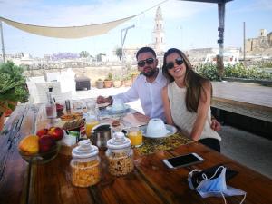 Un uomo e una donna seduti a un tavolo con del cibo di Azzurretta Guest House a Lecce