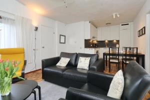 uma sala de estar com um sofá de couro preto e uma cozinha em Holiday home de Hollandsche Tulp em Noordwijkerhout