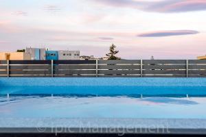 ハニア・タウンにあるCity center apartment with ROOFTOP swimming poolのフェンス前の青い水のスイミングプール