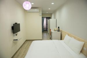 a bedroom with a white bed and a tv at Didi House無人化自助入住#附車位有限須預約 in Tainan