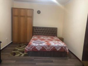 1 dormitorio con 1 cama y armario de madera en Guest House VIP, en Osh
