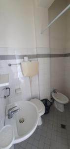 uma casa de banho branca com um lavatório e um WC em Arix Hotel em Rimini
