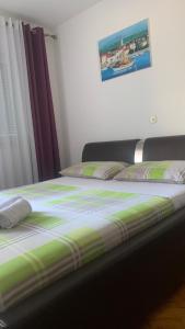 a bed with a green and white comforter in a room at Apartman Toni in Promajna