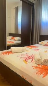 a bed with flowers on it in front of a mirror at Apartman Toni in Promajna