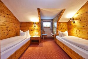 two beds in a room with wooden walls at Gästehaus Sonnenheim in Mittenwald