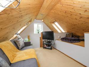 uma sala de estar com um sofá e uma televisão num sótão em Dalegarth em Ilminster