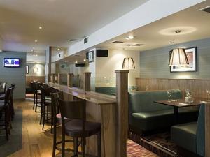 a restaurant with a bar with green chairs and tables at Orchard Park Hotel in Giffnock