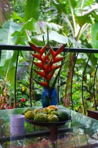 een blauwe vaas met rode bloemen op een tafel met fruit bij PAPAYAS SELF catering ROOM in Victoria