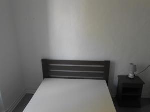 a bed in a room with a white wall at Au P'tit Dodo in Langogne